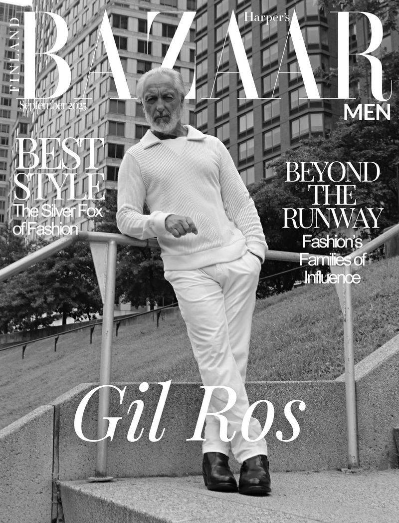 Black and white fashion magazine cover featuring a mature male model in white leaning against a railing with city buildings in background.