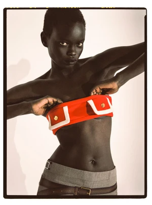 Athiec Geng wearing a red pocket-detail bandeau top and grey trousers against a light studio backdrop.