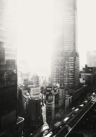 High-angle black and white shot of Tokyo cityscape with skyscrapers, busy streets, and signage on buildings during daytime.