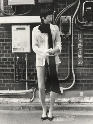 Model Meg Fuji posing against a brick wall with utility boxes in Tokyo for Manifesto Magazine