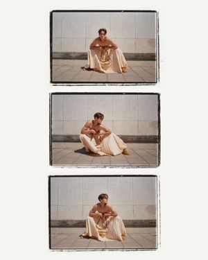Triptych of a shirtless man squatting outdoors wearing a cream pleated skirt against a stone wall for Behind the Blinds.