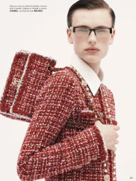 Model wearing a red tweed jacket and glasses holding a matching red tweed handbag against a white background.
