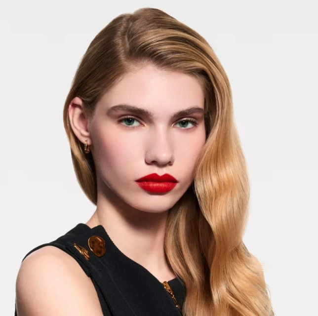 Close-up portrait of a young, blonde woman with vibrant red lipstick, showcasing beauty and makeup on a neutral background. Beauty advertisement.