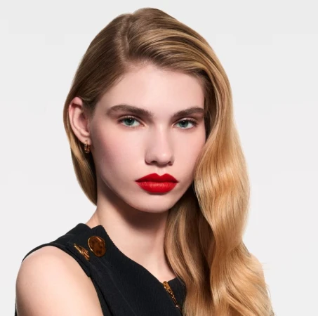 Close-up portrait of a young, blonde woman with vibrant red lipstick, showcasing beauty and makeup on a neutral background. Beauty advertisement.