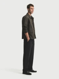 Model Clement Chabernaud wearing an olive jacket and dark trousers standing against a white backdrop