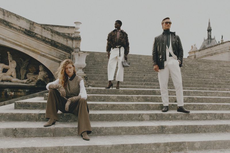 Three fashion models posing on stone steps near a building, wearing stylish clothing in an outdoor setting with natural lighting.