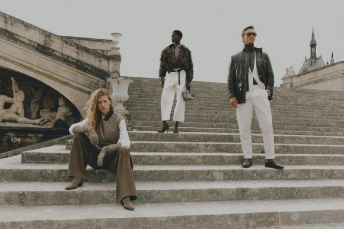 Three fashion models posing on stone steps near a building, wearing stylish clothing in an outdoor setting with natural lighting.