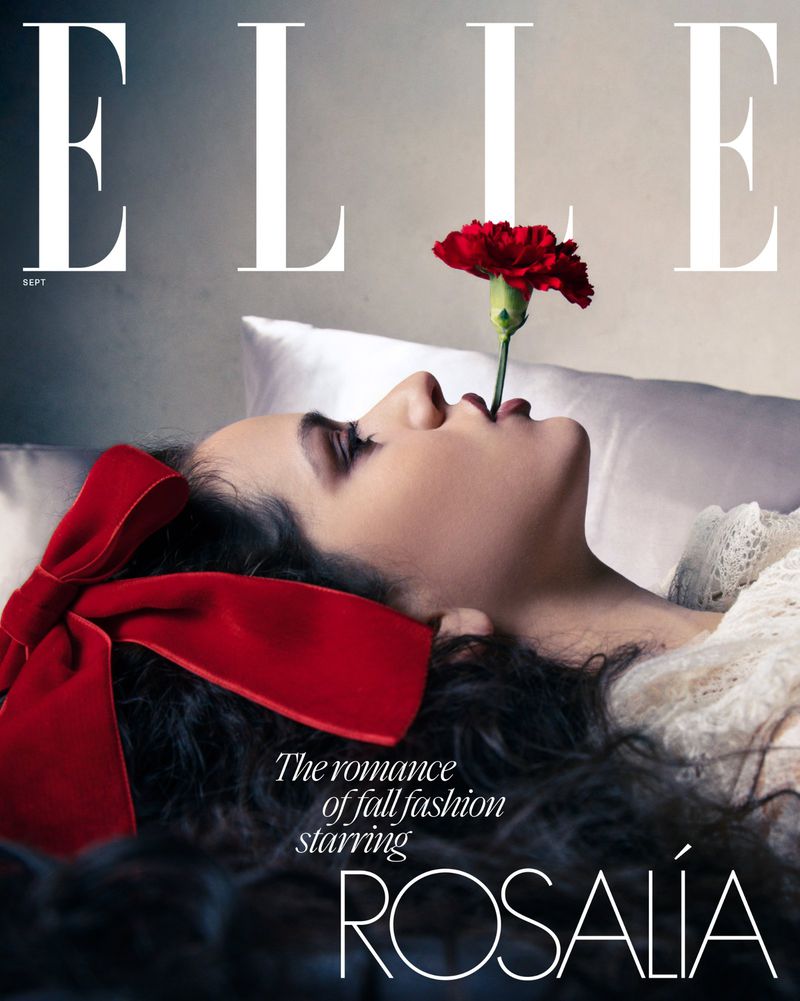 Elle magazine cover featuring a woman with a red flower in her mouth, laying down with a red bow in her hair, in a soft, diffused light.