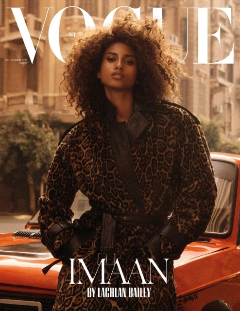 Vogue cover featuring Imaan Hammam in a leopard print coat, photographed by Lachlan Bailey. Building and vintage car in the background.