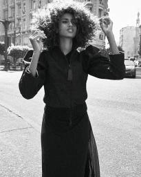 Model Imaan Hammam posing outdoors on a city street wearing a dark zip jacket and skirt, photographed by Lachlan Bailey for Vogue Netherlands.