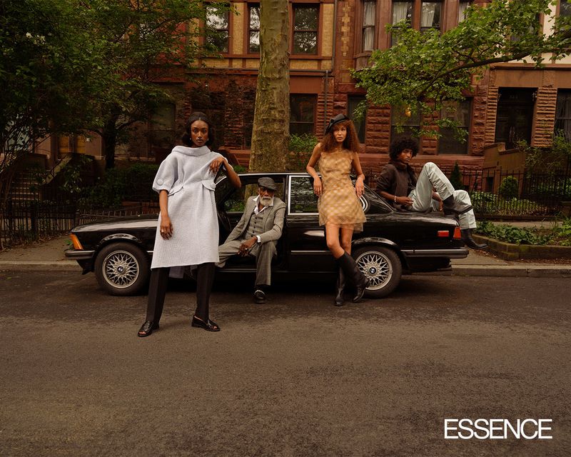 Editorial fashion shot featuring two women, one man leaning on vintage car with two seated people in front of a brownstone building.