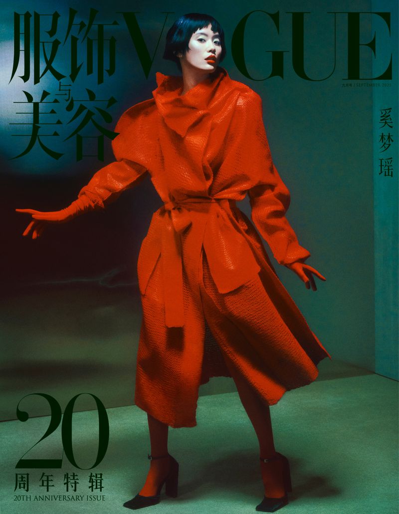 Vogue magazine cover featuring a stylish adult woman in a red coat and matching shoes against a soft, muted green backdrop.