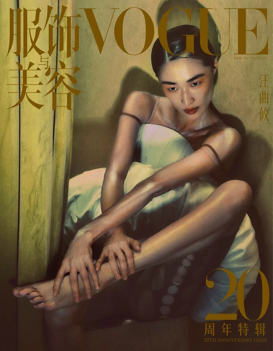 Model wearing a light-coloured strapless dress seated indoors with dramatic warm lighting for a Vogue China September 2025 cover.
