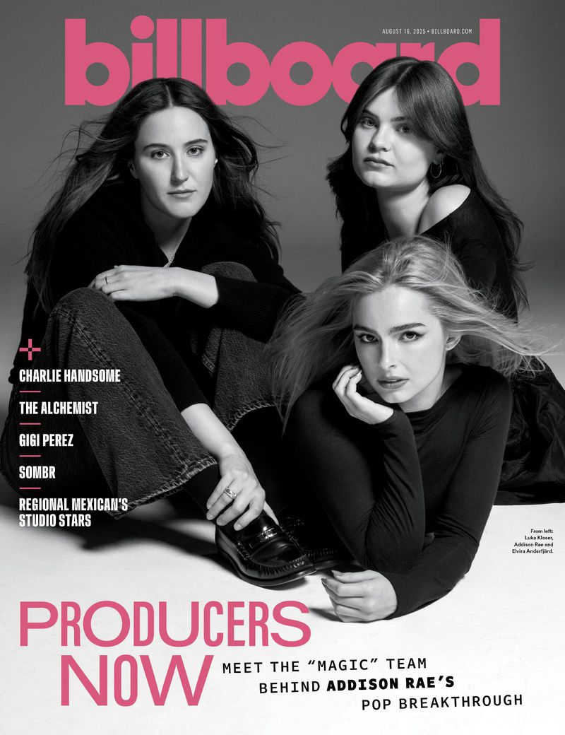 Billboard cover featuring three young women, dark clothing, posing indoors with magazine text and graphic elements in the frame.