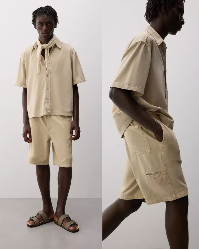 Two views of a slender adult male wearing a light tan, short-sleeved button-down shirt, matching shorts, leather sandals, and a scarf. 