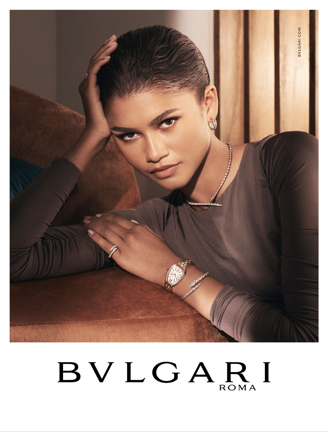 Zendaya posing with BVLGARI jewelry and watch, wearing a long-sleeved top and rings, with soft lighting and neutral colors in a close-up studio shot.