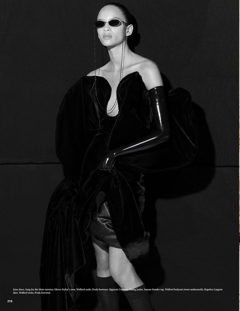 Fashion model in a black strapless gown with long black gloves poses against a dark background, showcasing an elegant and modern aesthetic.