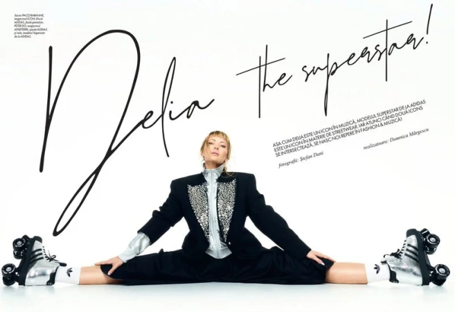 A blonde woman in a black blazer and roller skates does the splits in front of a white background with black script writing.