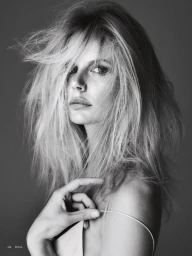 Black and white beauty portrait of model Marlijn Hoek with tousled hair holding a thin dress strap against a neutral studio background.