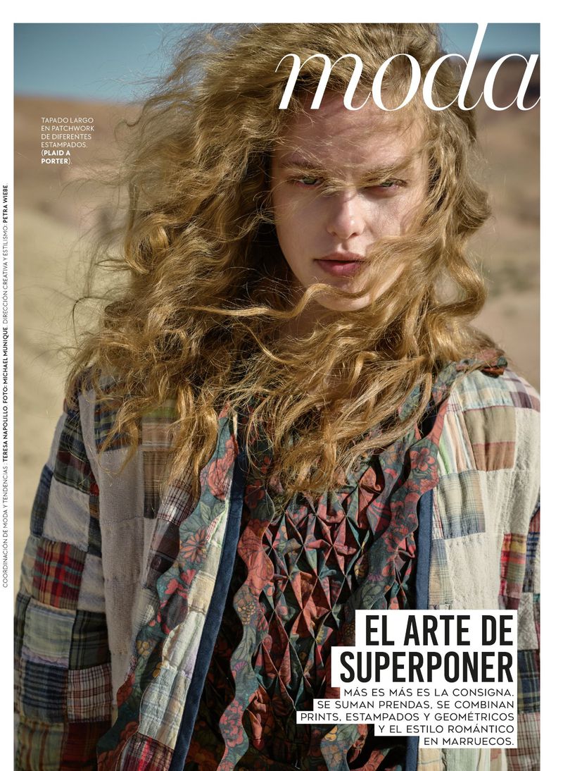 Magazine cover featuring a young adult with voluminous wavy hair wearing a patchwork jacket in front of a light-colored background.