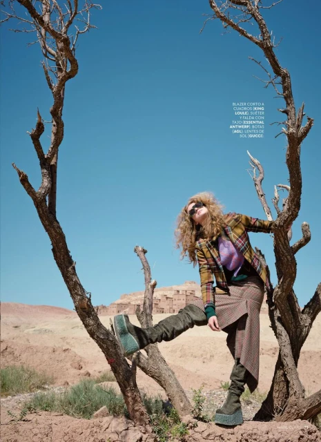 Model Esther Lomb posing in a desert landscape framed by dead tree branches for Marie Claire Argentina