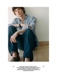 Young man in light blue linen shirt and dark denim jeans seated against a white wall for Massimo Dutti