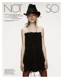 Model wearing a strapless black dress and black hat with red veiling against a white backdrop