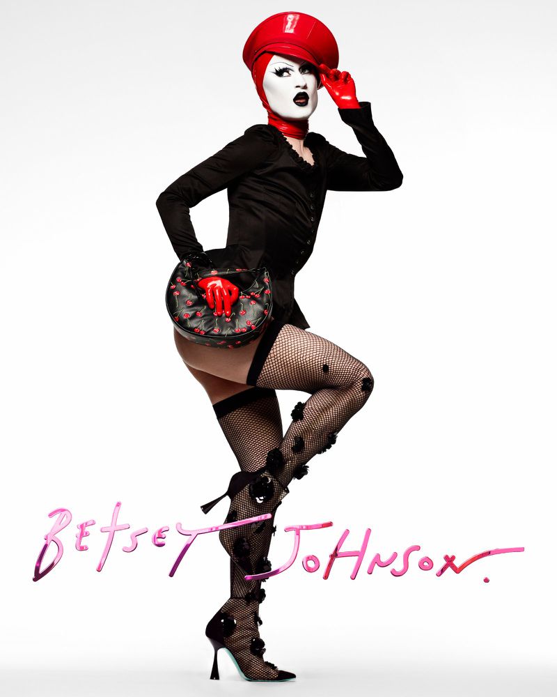 A person in striking black and red fashion poses against a white backdrop, showcasing a unique and bold aesthetic.