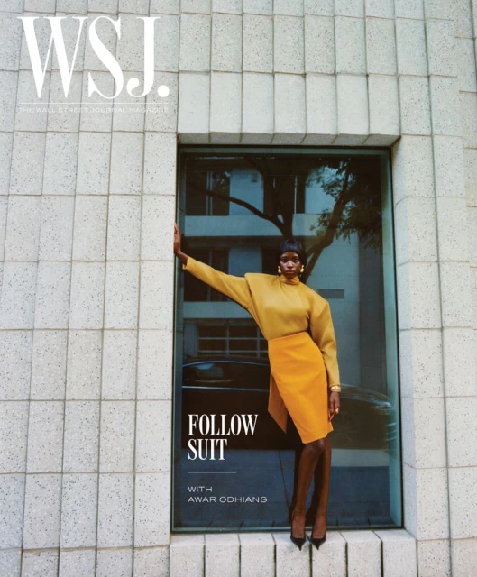 WSJ cover featuring a Black female fashion model in a yellow skirt suit standing in front of a window on a city street.