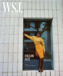 Model Awar Odhiang posing in a building window alcove wearing a mustard yellow top, bright yellow skirt, and black heels.