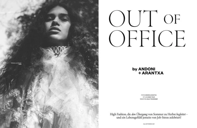 Fashion editorial image of a woman with curly hair wearing an ornate white collar and dress, posing outdoors in a black and white photograph.