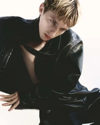 Troye Sivan wearing a black leather jacket against a bright white background