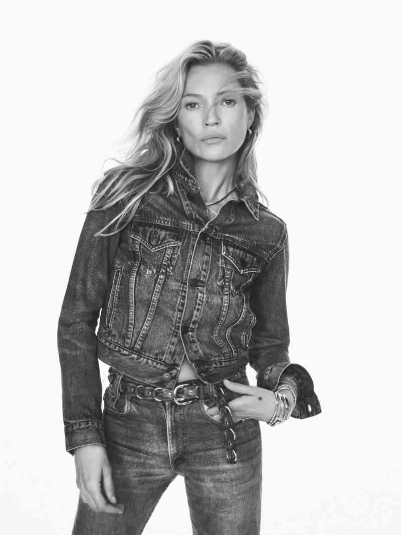 Kate Moss posing in a denim jacket and matching jeans against a bright white background.