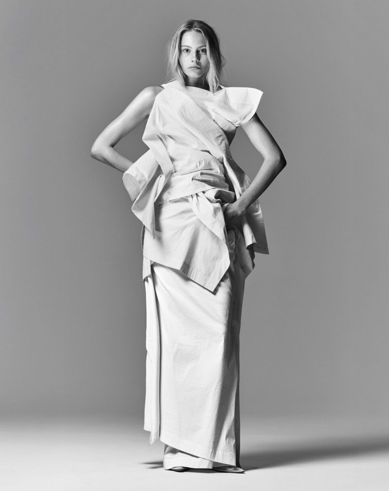 Model Annie Arnander wearing a structured white dress in a monochrome fashion editorial portrait against a seamless grey backdrop.