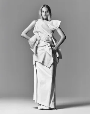 Model Annie Arnander wearing a structured white dress in a monochrome fashion editorial portrait against a seamless grey backdrop.