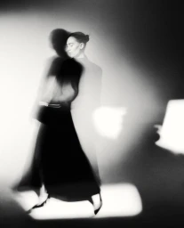 Monochrome portrait of actress Vanessa Kirby with motion blur captured against a plain studio background.