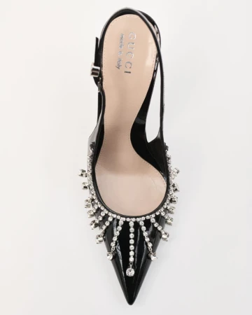 Elevated view of a glossy black slingback high heel pump from Gucci, featuring an elegant jeweled fringe on a white backdrop.