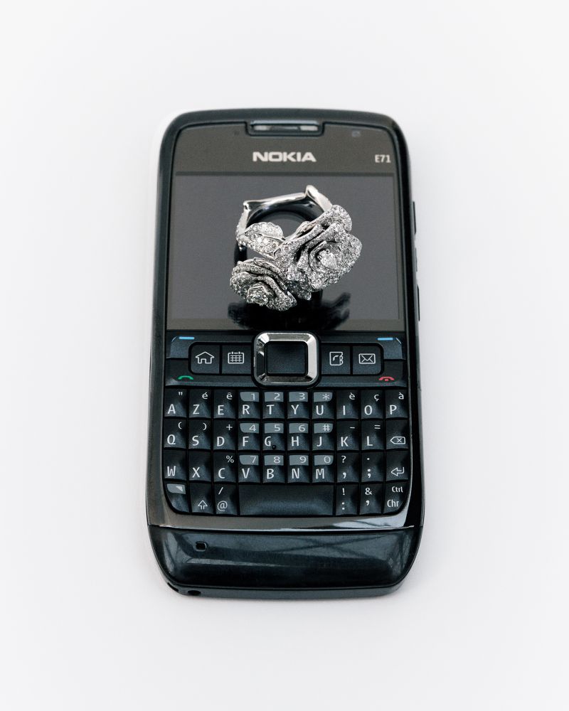 Diamond ring on a black Nokia E71 cell phone against a white background. High-angle, close-up shot displaying jewellery and technology.