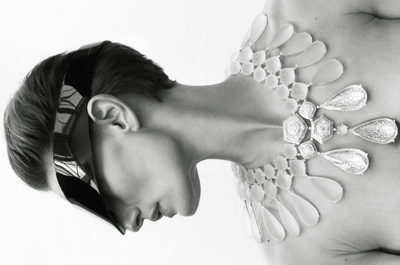 Monochrome profile portrait of model Veronika Kunz wearing a geometric statement necklace and futuristic visor sunglasses.