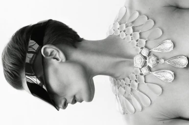 Monochrome profile portrait of model Veronika Kunz wearing a geometric statement necklace and futuristic visor sunglasses.