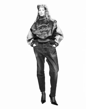 Model in varsity jacket and jeans standing against white seamless background for Harper's Bazaar Italia editorial