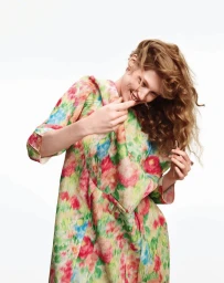 Model in a floral print dress playfully twirling her hair against a plain white background for Harper's Bazaar Italia