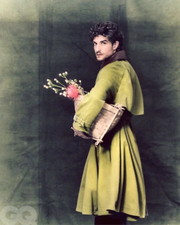 Man in a green coat holding flowers in a basket on green background. Portrait shot of a man in fashionable outerwear.