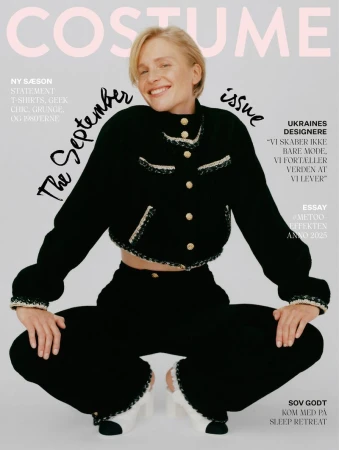 Model Steffi Cook smiling in a black tweed jacket and trousers against a neutral background for Costume Denmark