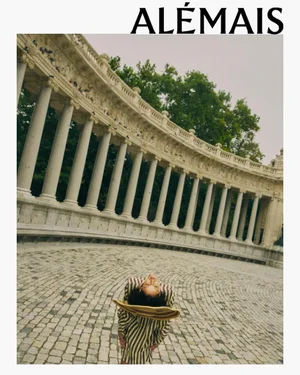 Model wearing striped clothing bending backward against a paved public square with classic columns
