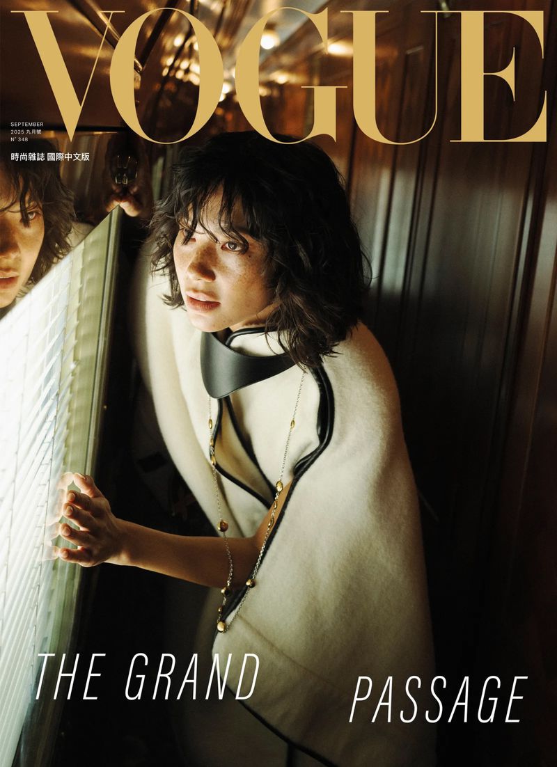 Vogue magazine cover featuring a woman with dark hair and a cream-colored coat, looking at a window, with the title 'The Grand Passage'.