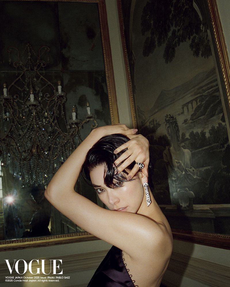 Elegant woman poses with wet hair and jewelry in front of ornate mirror and chandelier, Vogue Japan cover, October 2023.