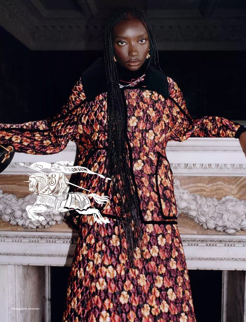 Elegant Black woman poses in a floral coat and skirt in front of a marble fireplace. The composition showcases fashion and luxury.