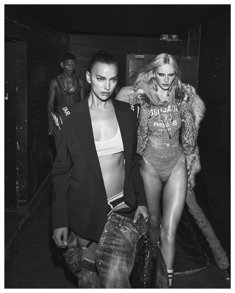 Black-and-white fashion photo of three models in streetwear and athletic-leisure wear, posing indoors with dark background and gritty mood.