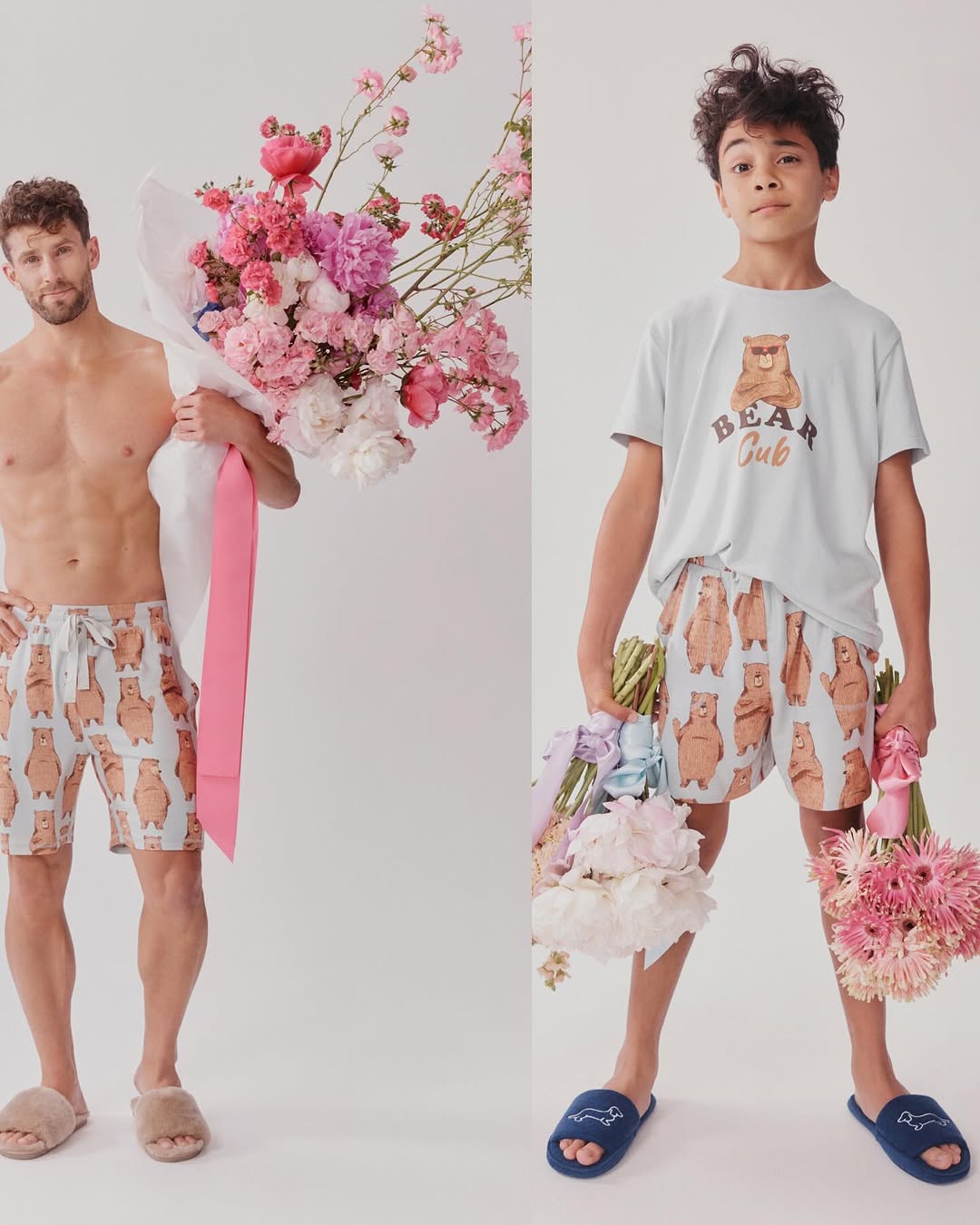 Adult male and child model matching loungewear with bear pattern. Man holds pink bouquet; boy holds pink and white flowers in a studio setting.